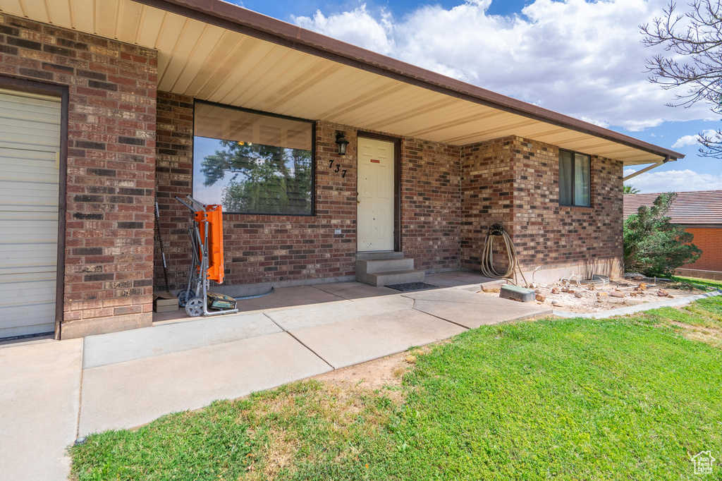 Entrance to property with a yard and brick siding