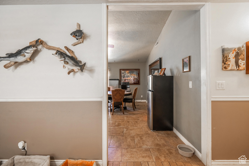 Hall with a textured ceiling and baseboards