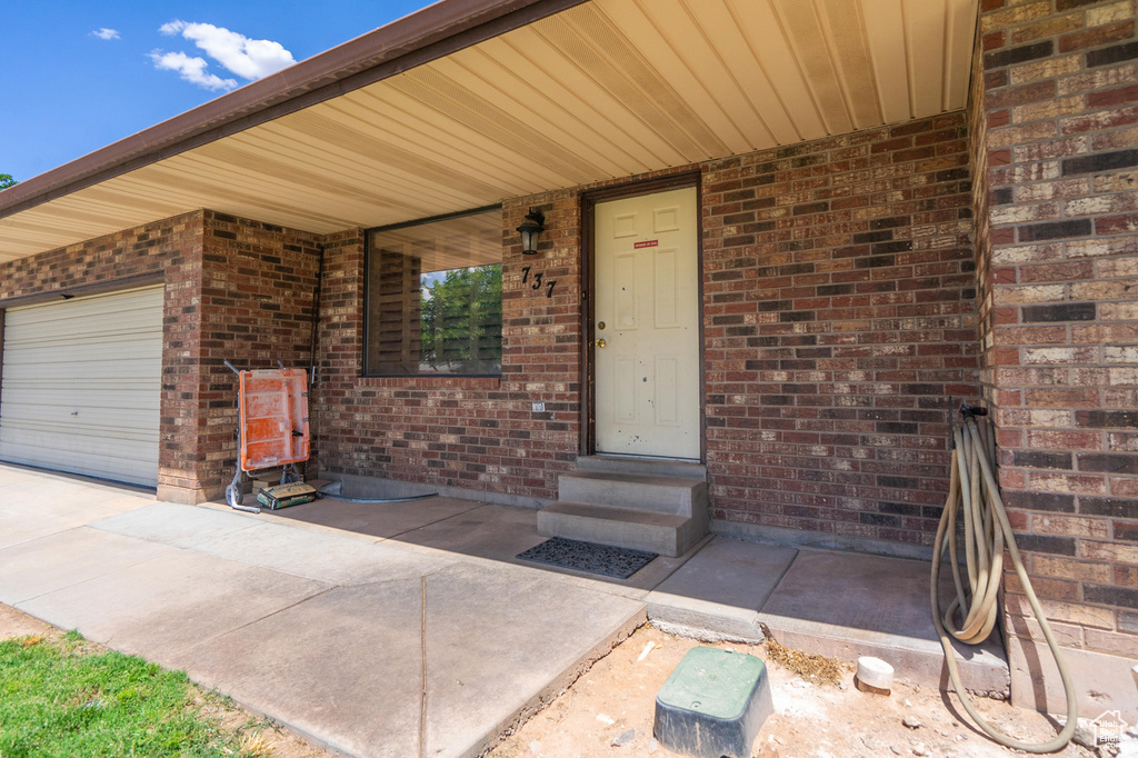 Doorway to property featuring brick siding and a garage