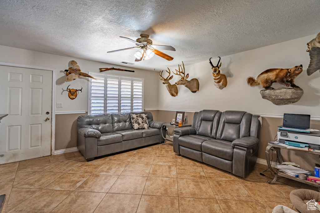 Living room with a ceiling fan, a textured ceiling, and light tile patterned floors