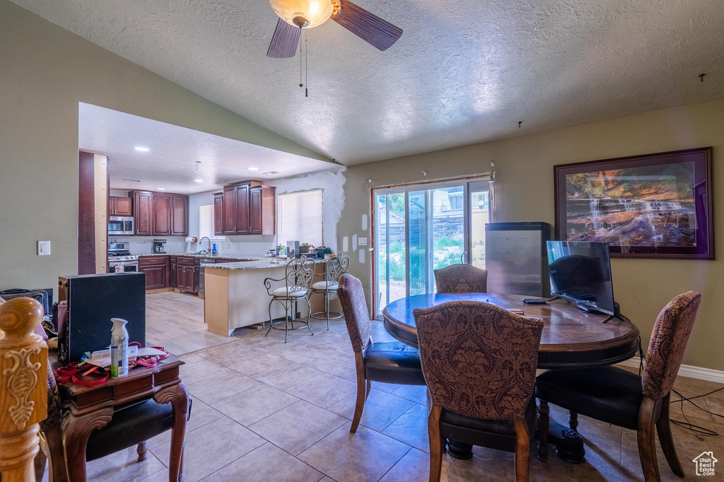 Dining area featuring a textured ceiling, lofted ceiling, and ceiling fan