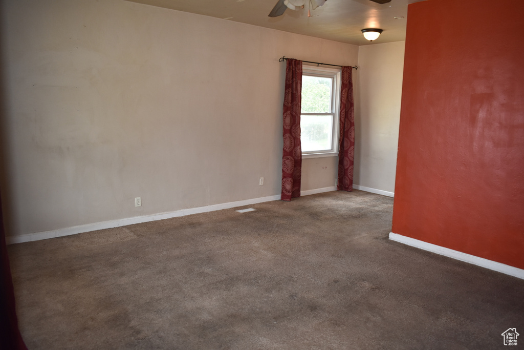 Carpeted spare room with a ceiling fan and baseboards