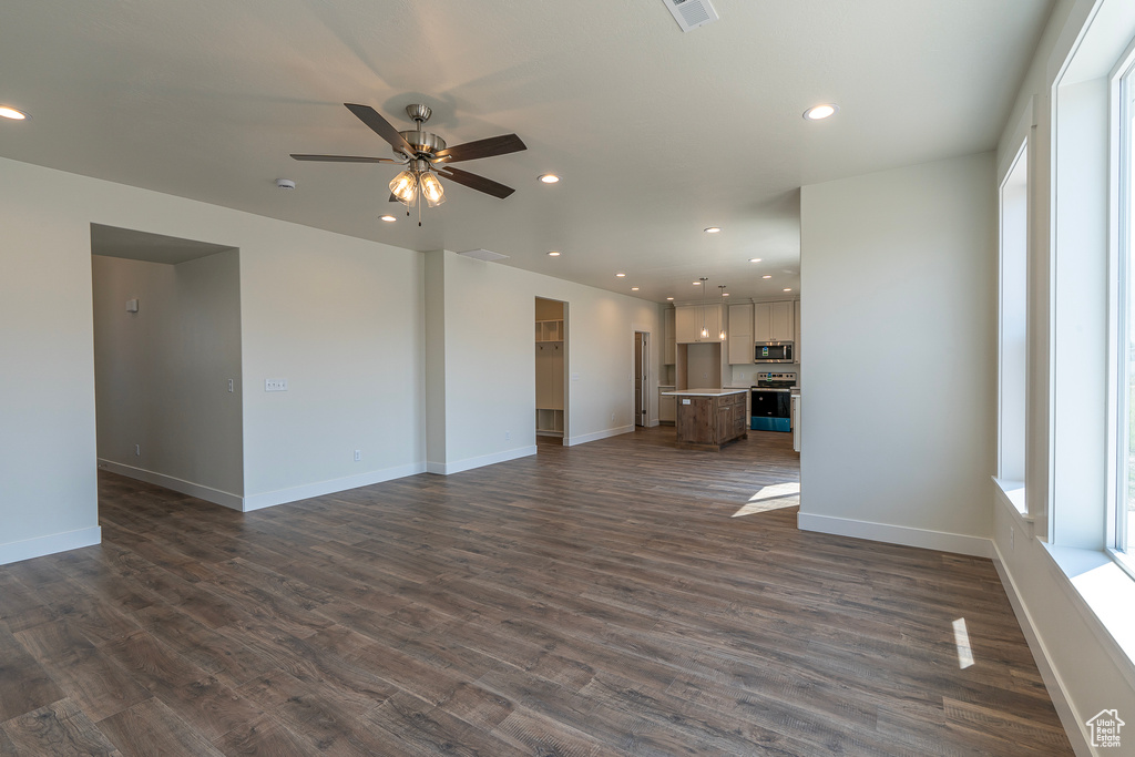 Unfurnished living room featuring a ceiling fan, dark wood-type flooring, and recessed lighting