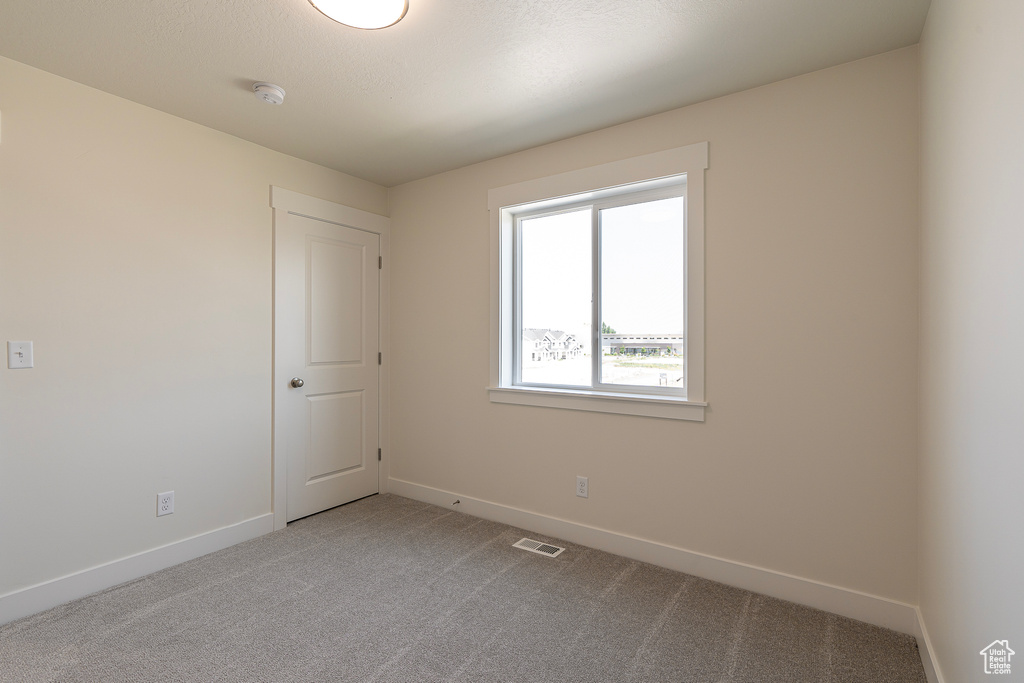 Carpeted spare room featuring baseboards and a smoke detector
