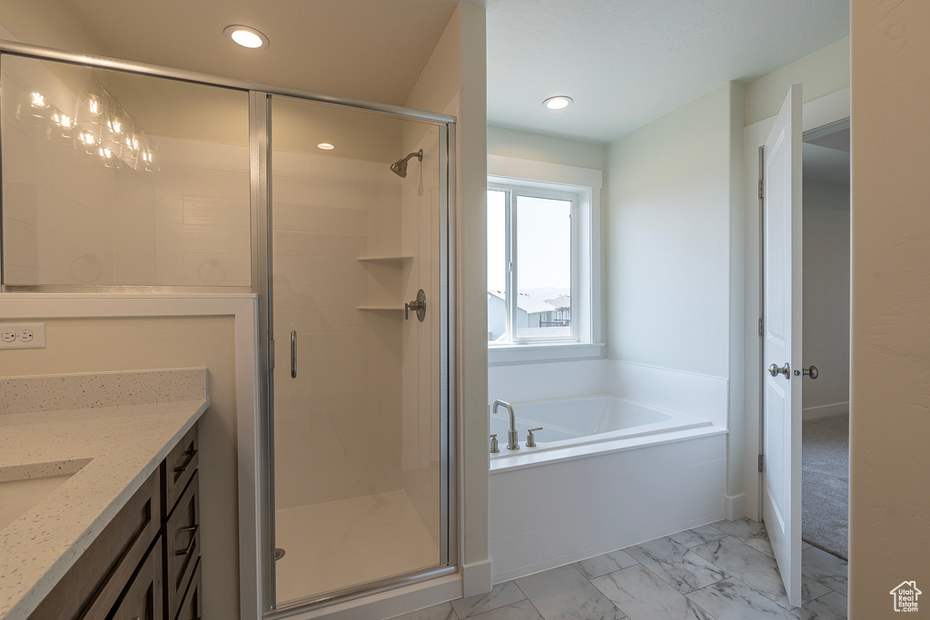 Bathroom featuring marble look tile flooring, a bath, a shower stall, vanity, and recessed lighting