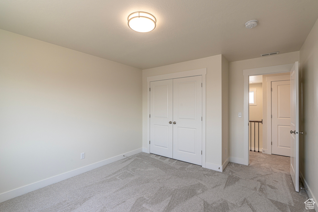 Unfurnished bedroom featuring light colored carpet and a closet