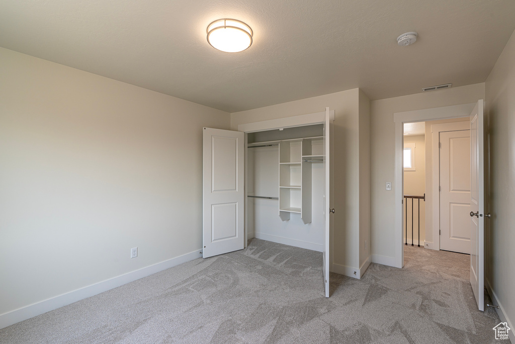 Unfurnished bedroom with light colored carpet and a closet