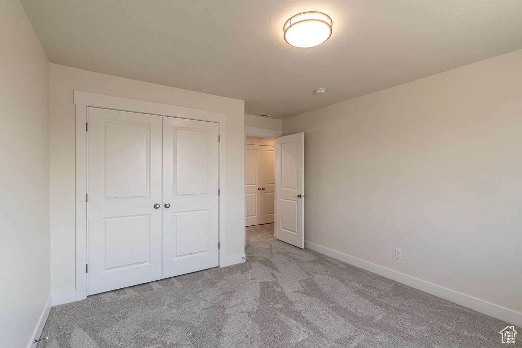 Unfurnished bedroom with light colored carpet and a closet