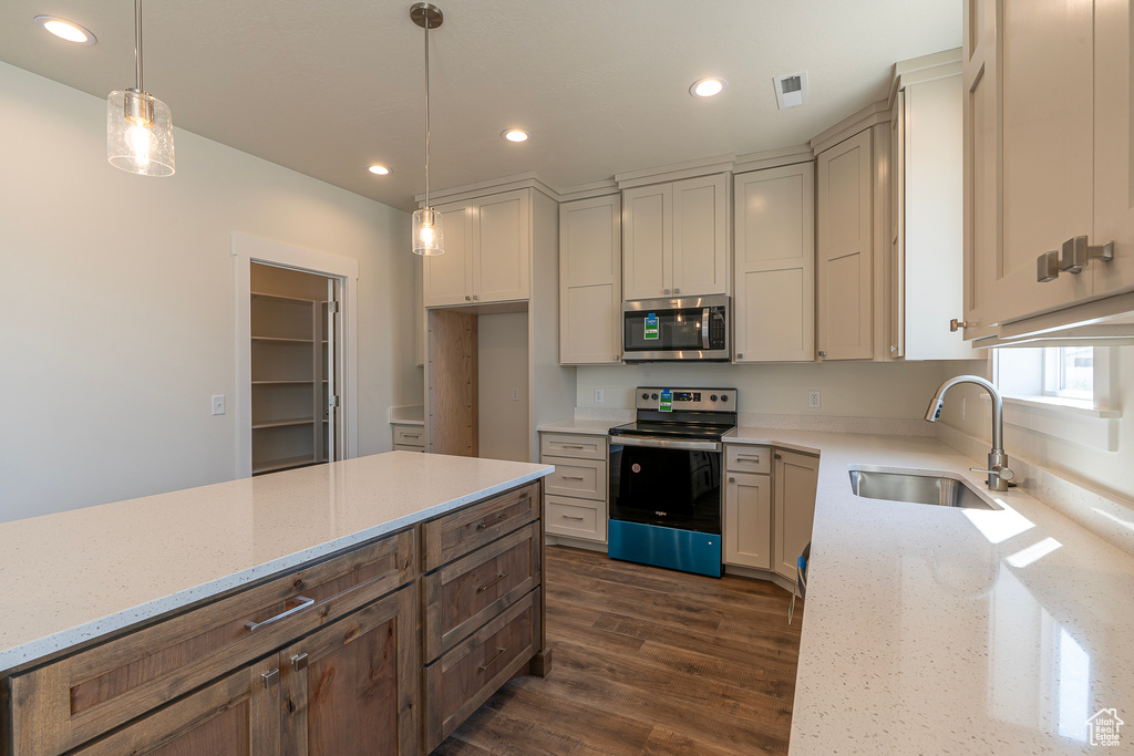 Kitchen featuring stainless steel appliances, light stone countertops, dark wood finished floors, recessed lighting, and hanging light fixtures
