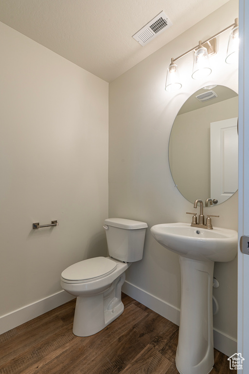 Half bath with toilet and wood finished floors