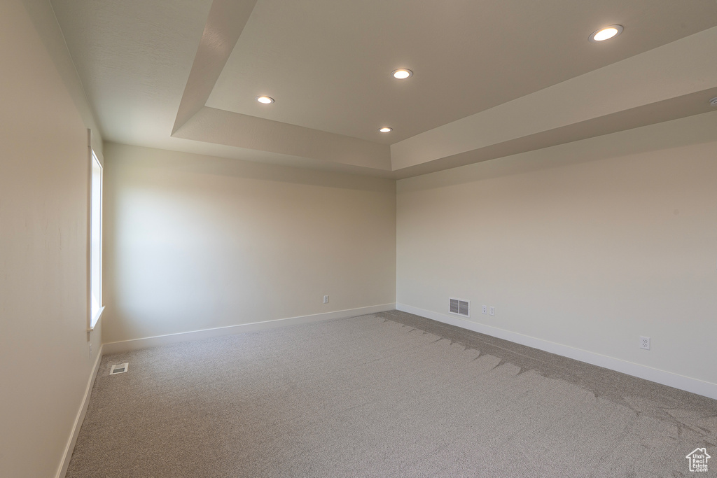 Unfurnished room with recessed lighting, light colored carpet, and a raised ceiling