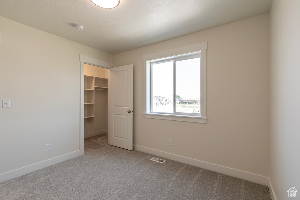 Unfurnished bedroom with carpet flooring, a walk in closet, and a closet