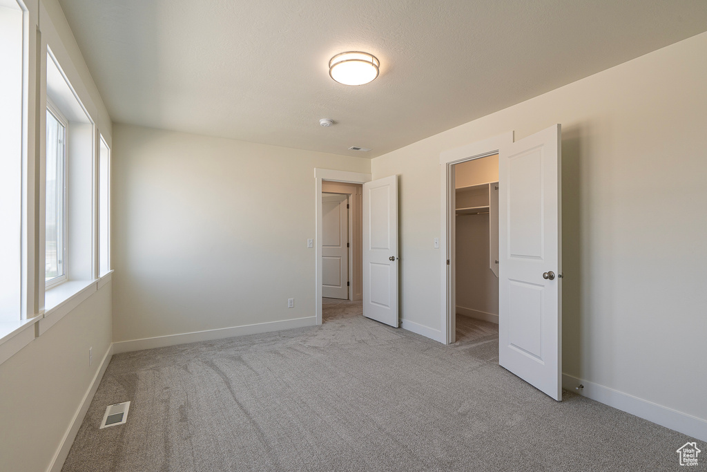 Unfurnished bedroom with carpet floors, a spacious closet, and a closet