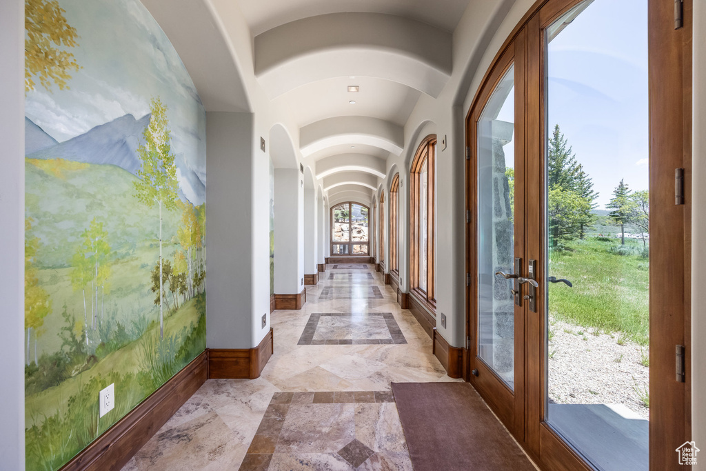Entrance foyer featuring french doors, lofted ceiling, light marble finish floors, and arched walkways