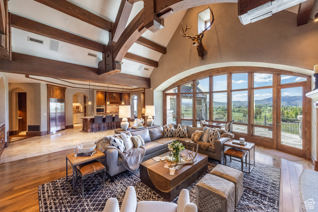 Living area featuring arched walkways, beam ceiling, light wood-style floors, high vaulted ceiling, and a mountain view