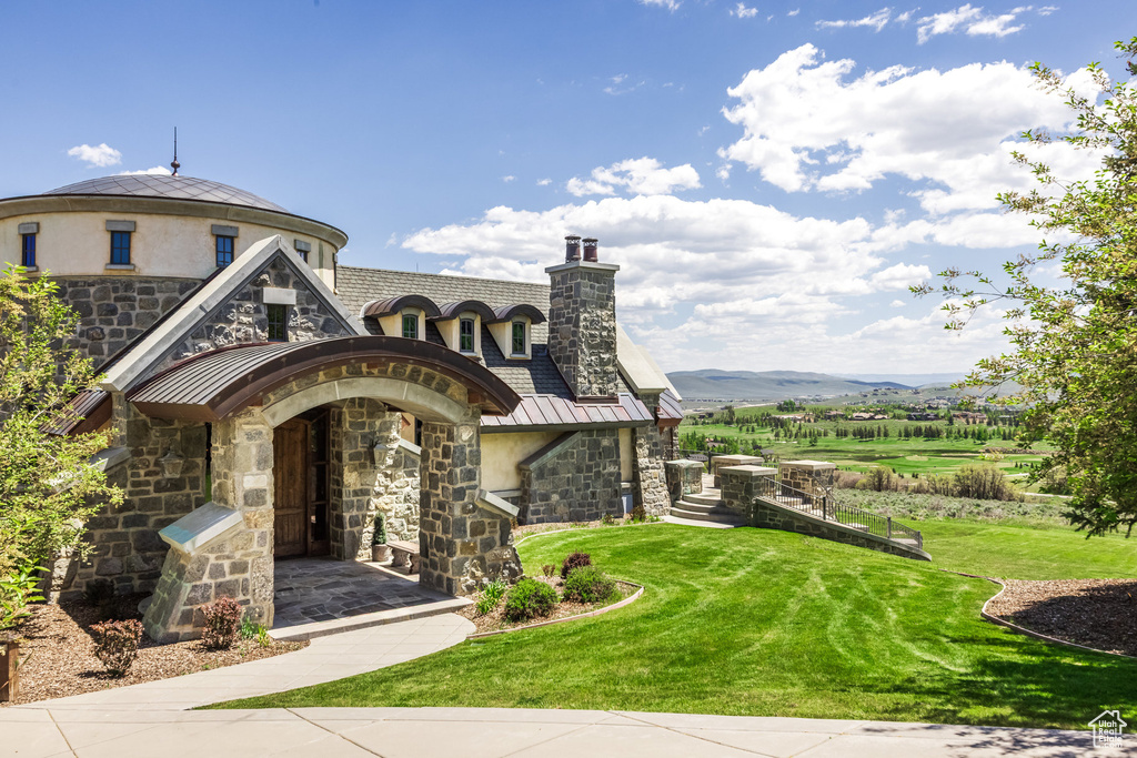 View of front of property with stone siding, stucco siding, a chimney, and a front lawn