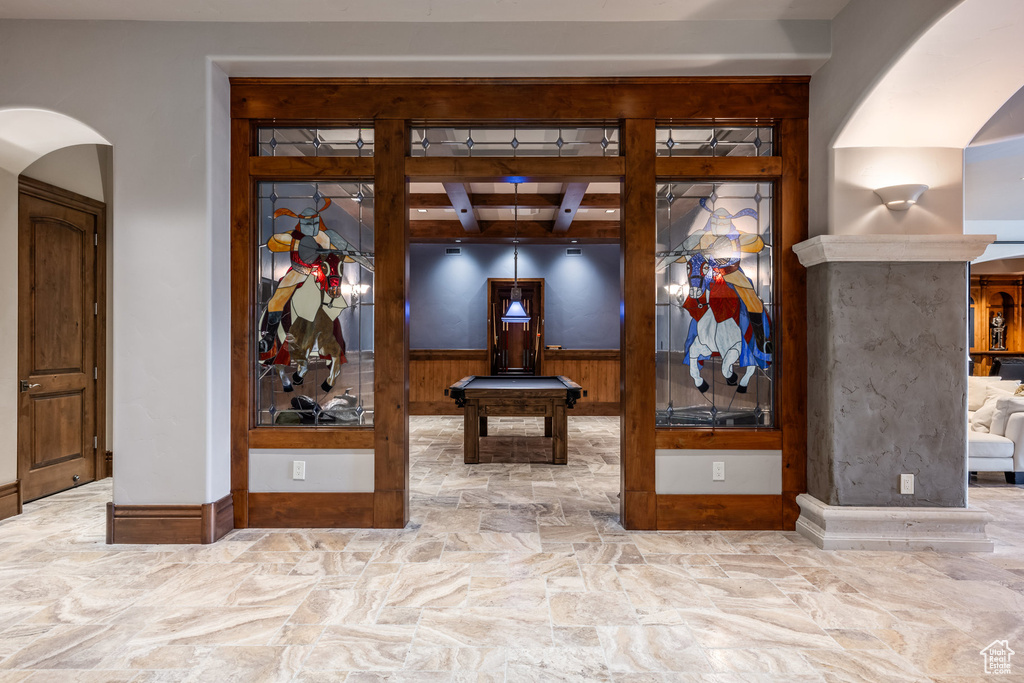 Hall featuring arched walkways, stone finish flooring, and beam ceiling