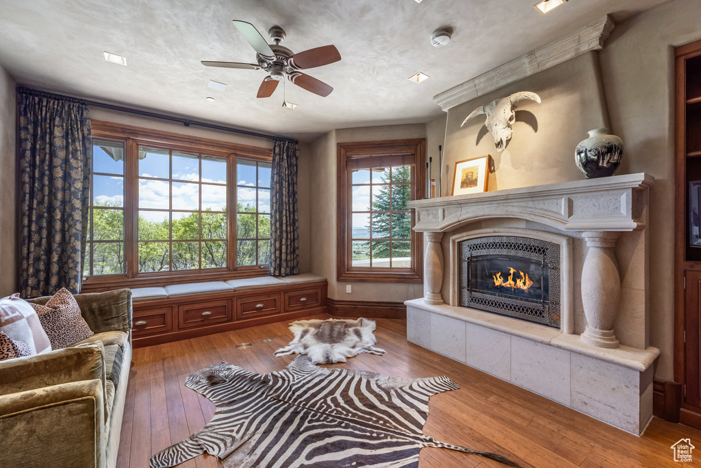 Living room with wood-type flooring, a fireplace, and ceiling fan
