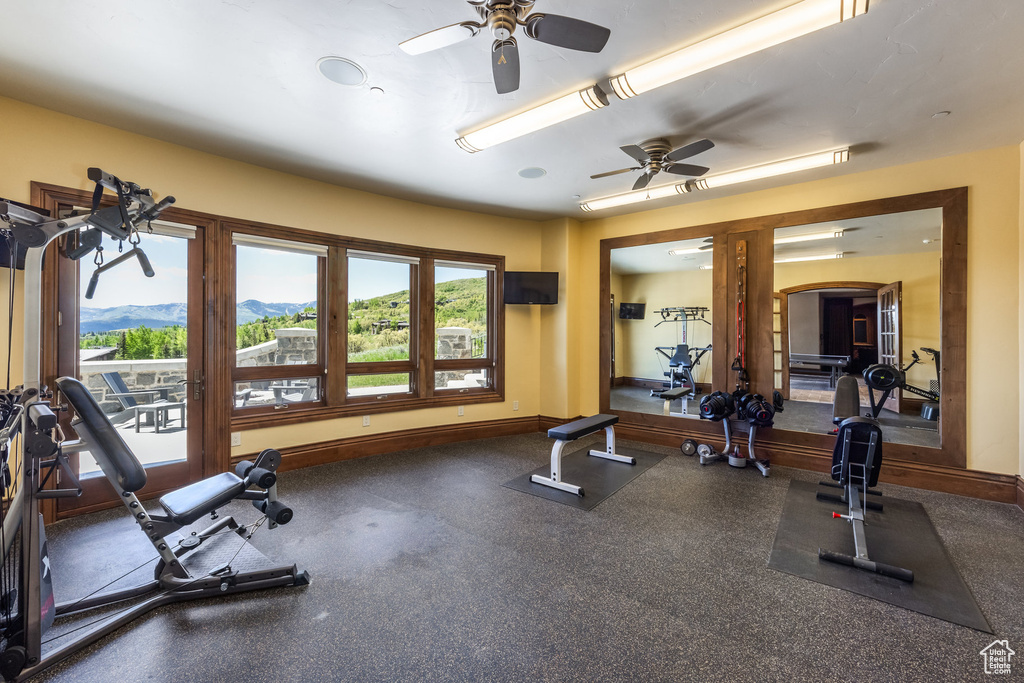 Exercise room with ceiling fan and baseboards