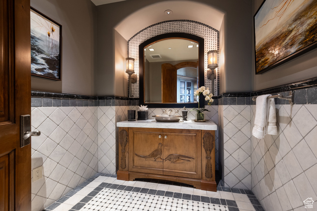 Bathroom with tile walls, vanity, wainscoting, and tile patterned flooring