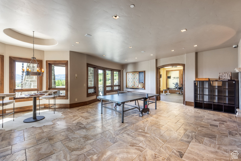 Game room featuring stone tile floors, arched walkways, a chandelier, and recessed lighting