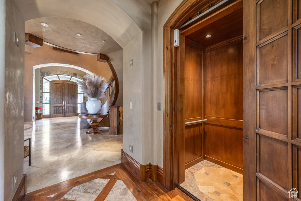 Hall with arched walkways, inlaid floor details, and elevator