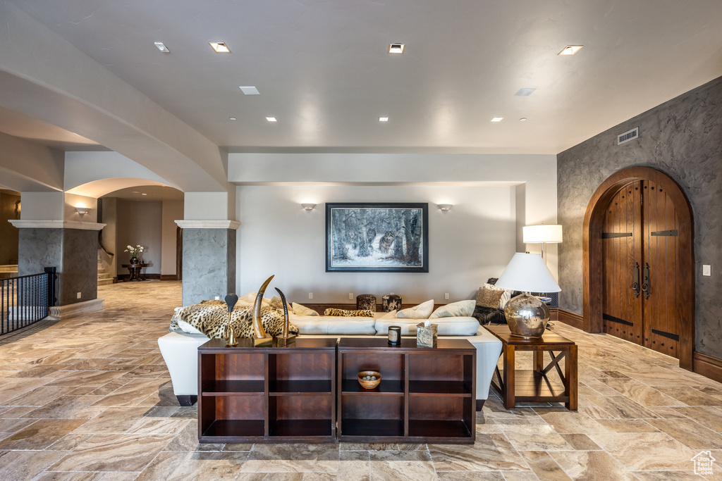 Living room featuring arched walkways, stone tile flooring, recessed lighting, and a premium fireplace