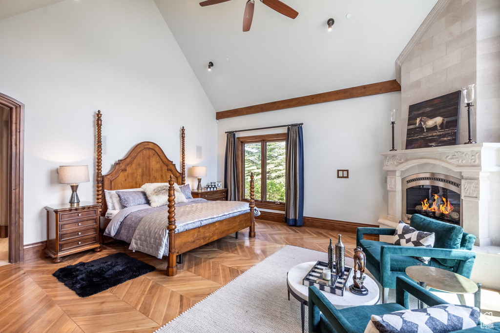 Bedroom featuring a glass covered fireplace, high vaulted ceiling, and a ceiling fan