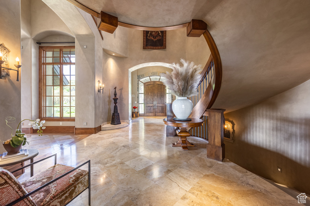 Foyer with arched walkways, a high ceiling, and marble tiled floors