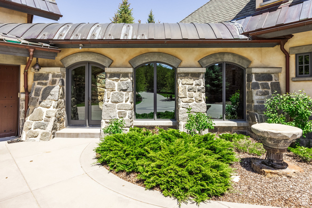 Doorway to property with a standing seam roof, stone siding, french doors, and a metal roof