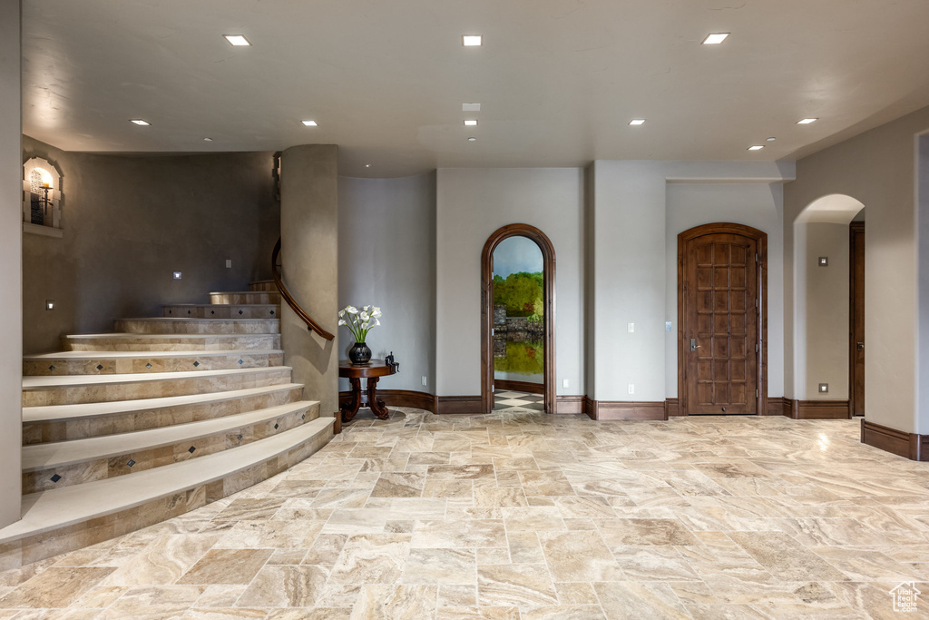 Entrance foyer featuring arched walkways, stone floors, recessed lighting, and stairs