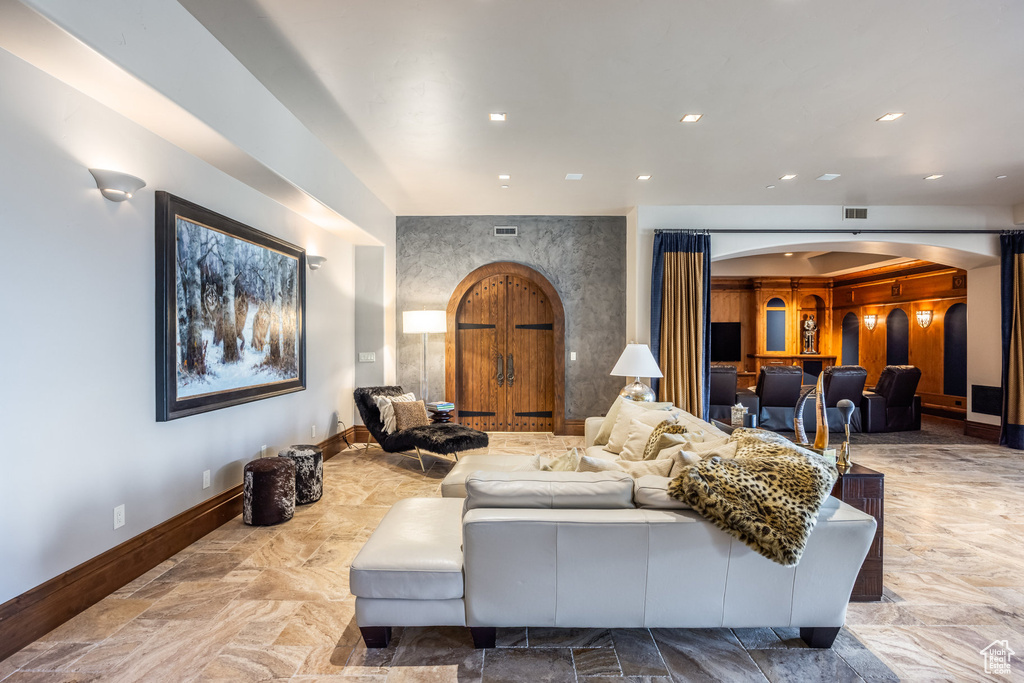 Living room with arched walkways, stone finish flooring, and recessed lighting