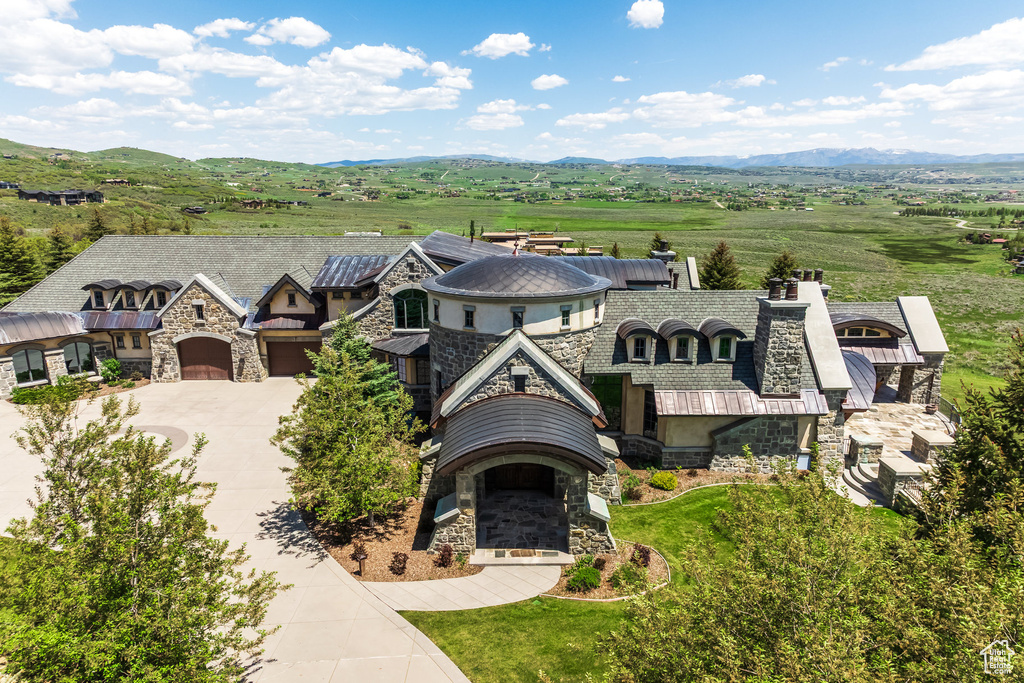 View of front facade featuring stone siding, an attached garage, driveway, a mountain view, and stucco siding