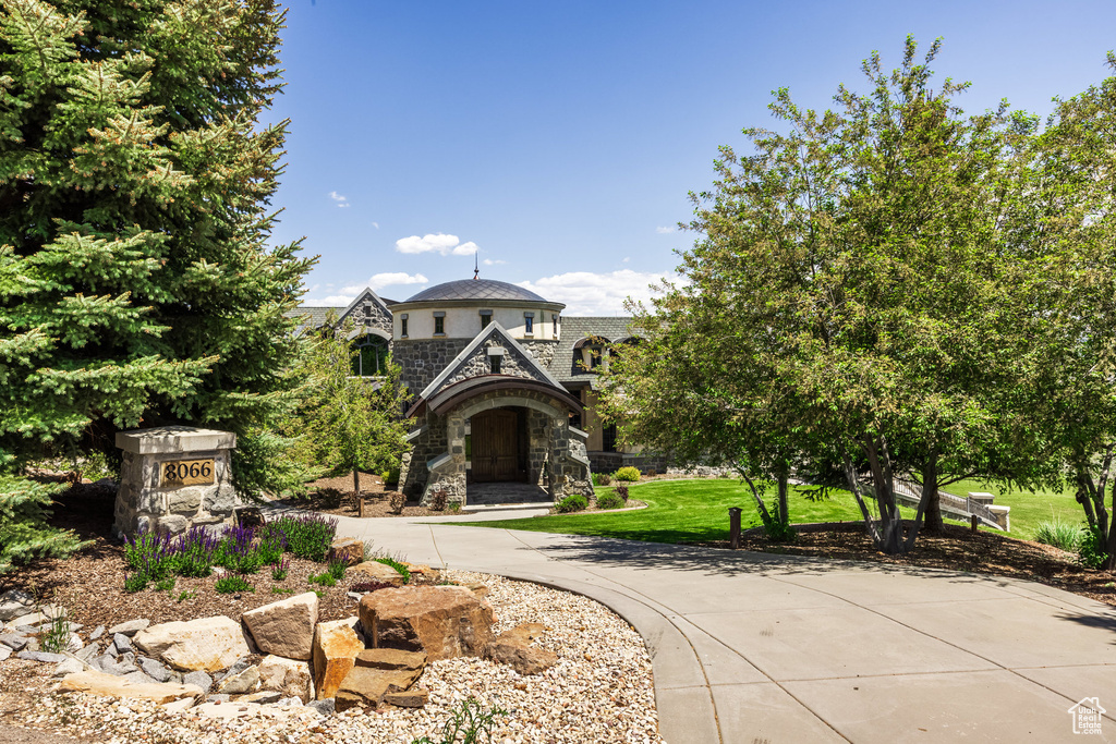 View of front facade with stone siding, a high end roof, and a front yard