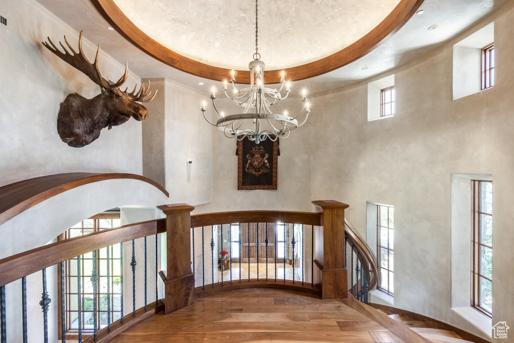 Hallway with a chandelier, wood finished floors, stairs, and a towering ceiling