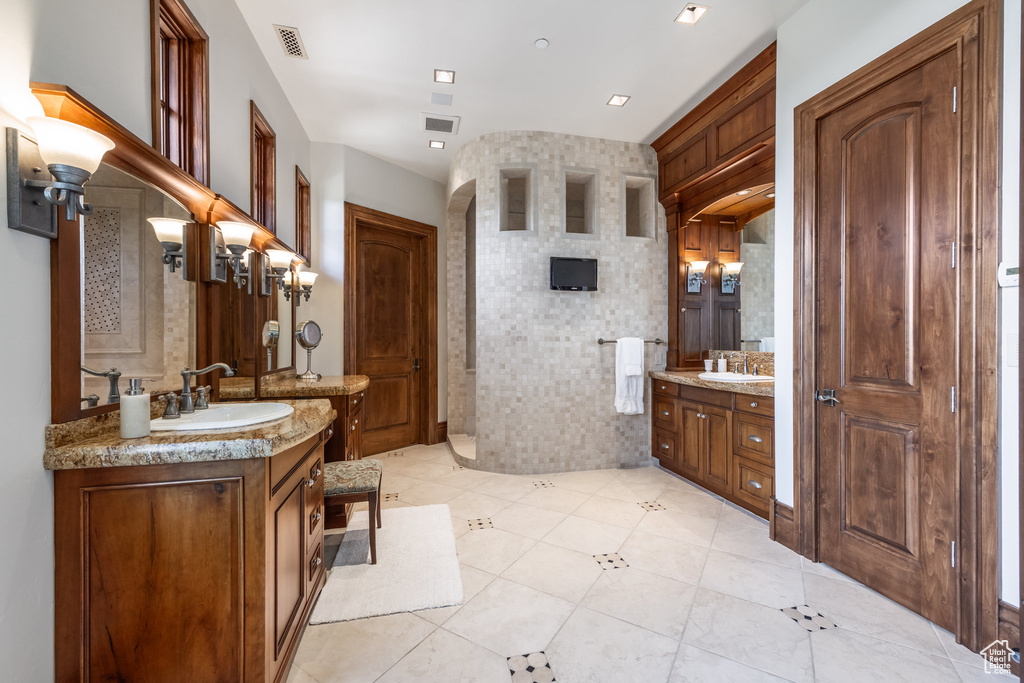 Full bath with two vanities, tile patterned floors, and tiled shower