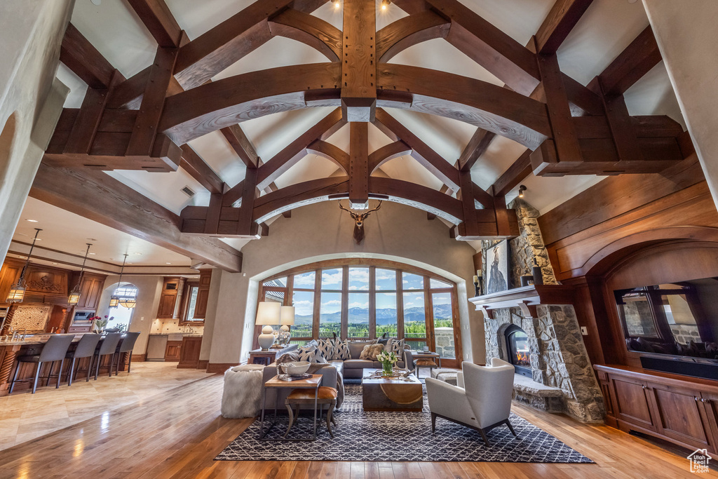 Living area with healthy amount of natural light, light wood-style floors, a fireplace, beam ceiling, and high vaulted ceiling