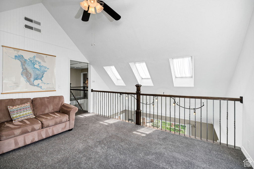 Carpeted living room featuring a skylight, vaulted ceiling, and ceiling fan