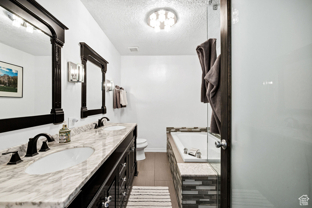 Bathroom with double vanity, a garden tub, a textured ceiling, and wood finished floors
