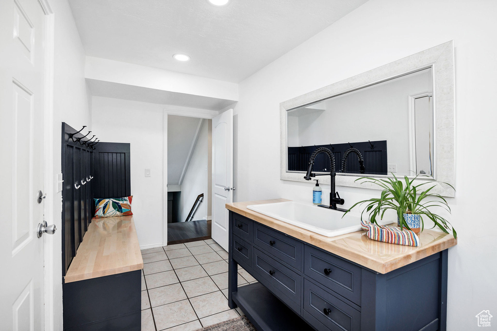Kitchen featuring wood counters, blue cabinetry, light tile patterned flooring, and recessed lighting