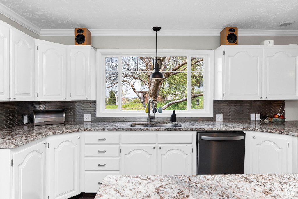 Kitchen with stainless steel dishwasher, light stone countertops, white cabinets, tasteful backsplash, and ornamental molding