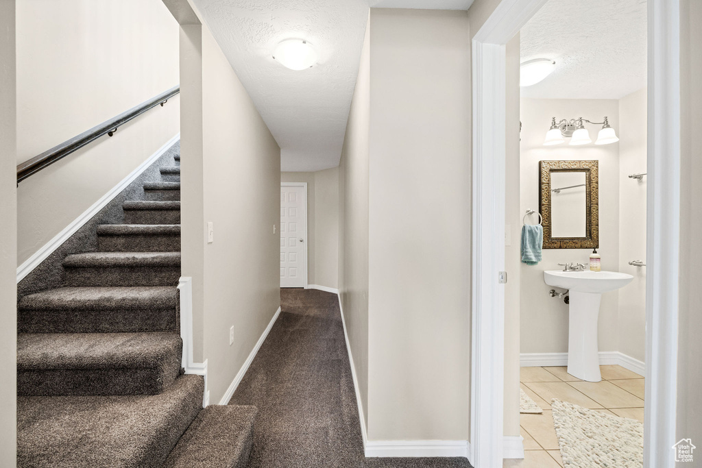 Stairs with tile patterned flooring and a textured ceiling