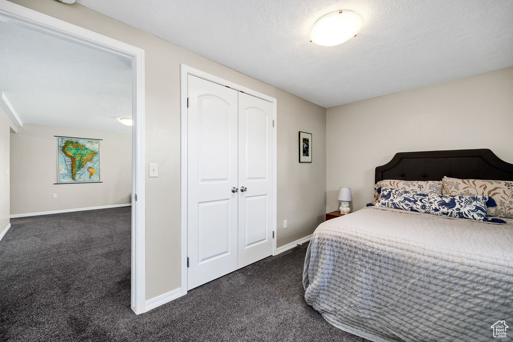 Bedroom with dark carpet and a closet
