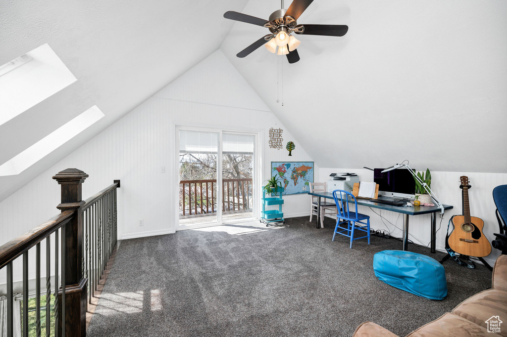 Carpeted office featuring lofted ceiling, a skylight, and ceiling fan
