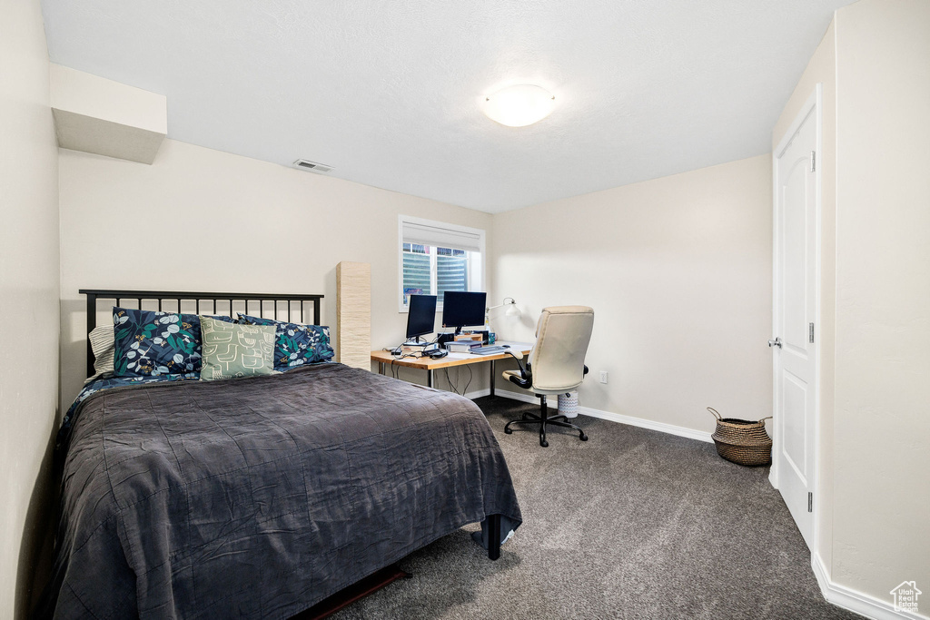 Carpeted bedroom featuring baseboards and an office area