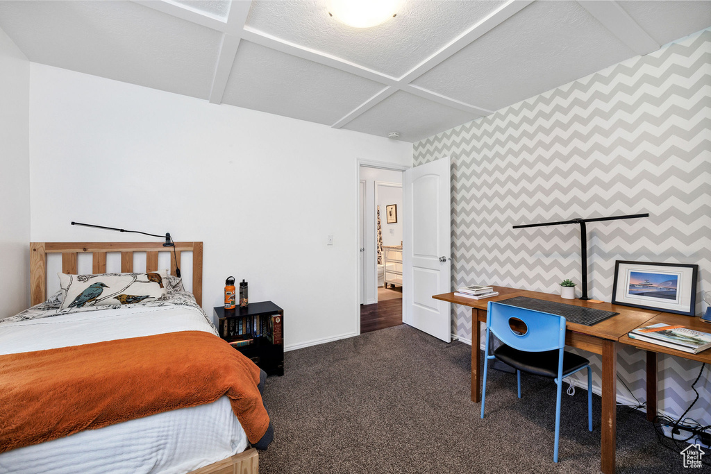 Bedroom with wallpapered walls, dark colored carpet, and a desk