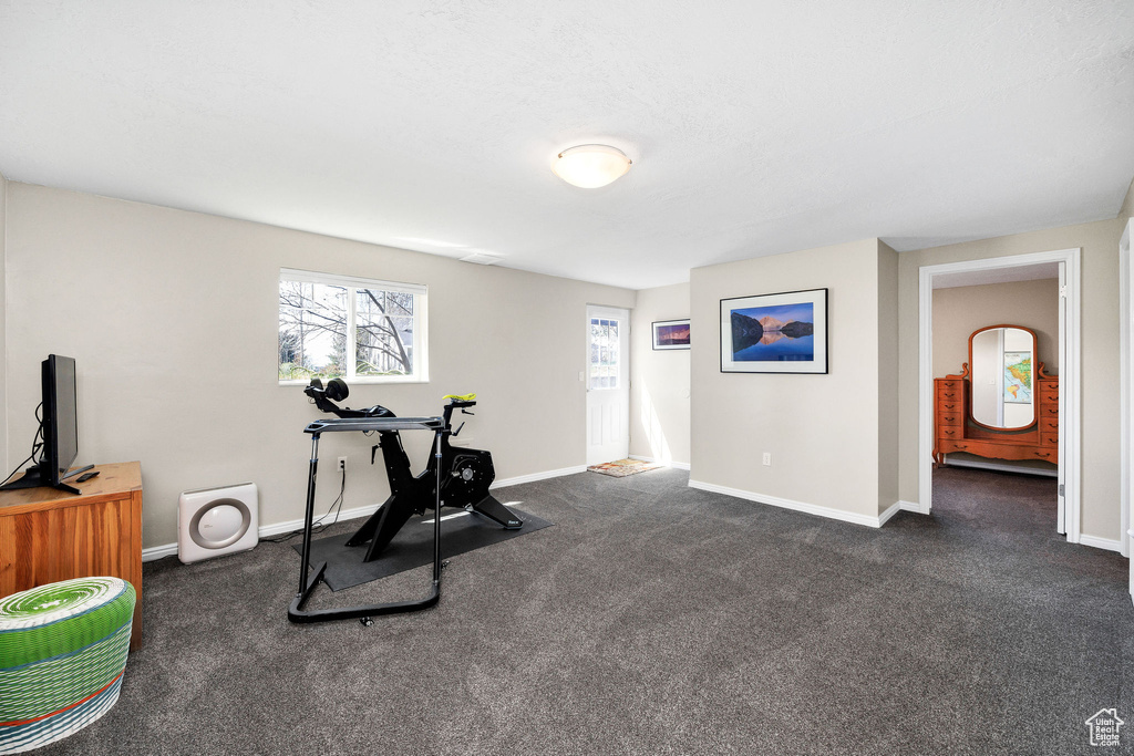 Exercise area featuring dark colored carpet and baseboards