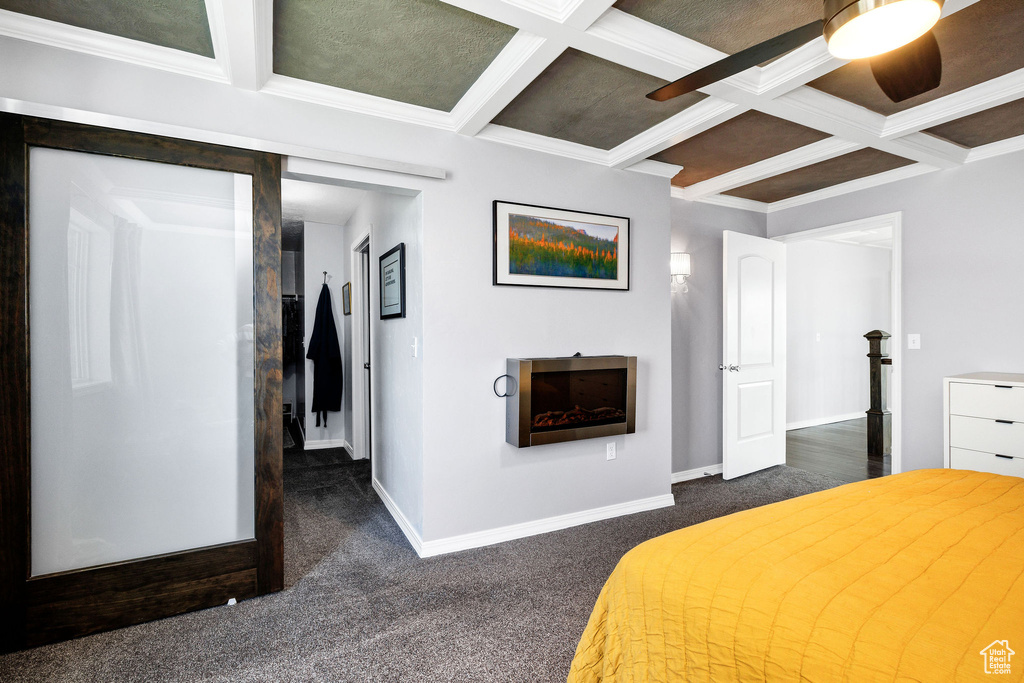 Bedroom with dark carpet, coffered ceiling, a fireplace, beamed ceiling, and ornamental molding