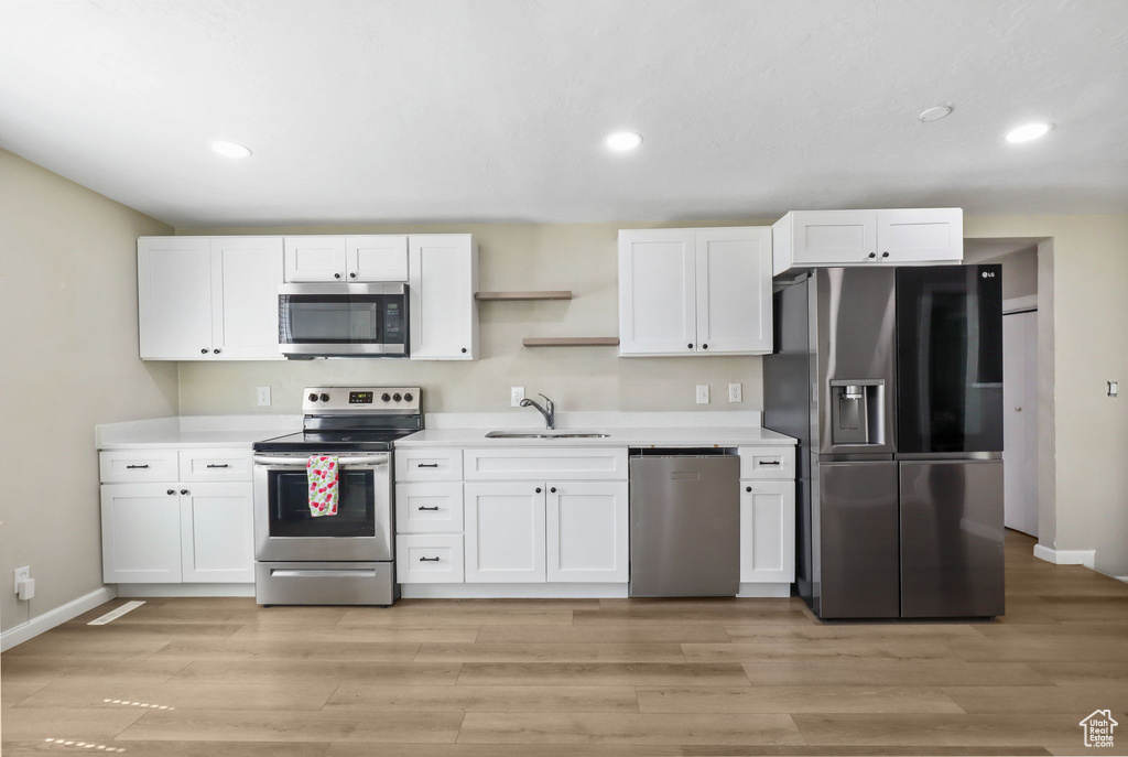 Kitchen featuring stainless steel appliances, white cabinets, light countertops, recessed lighting, and light wood-style flooring