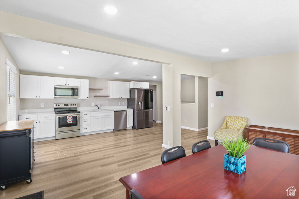 Dining area with light wood finished floors and recessed lighting